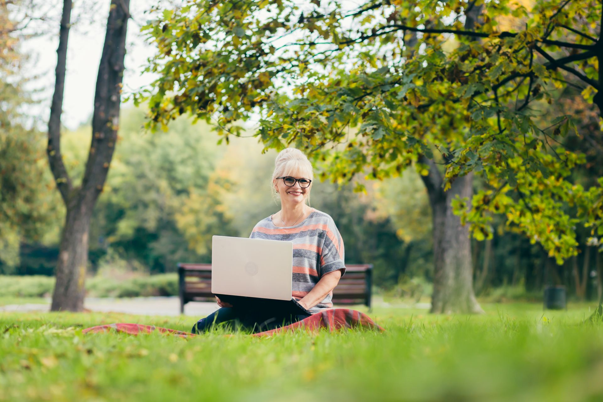 Woman doing advance funeral planning on a laptop in a natural burial ground