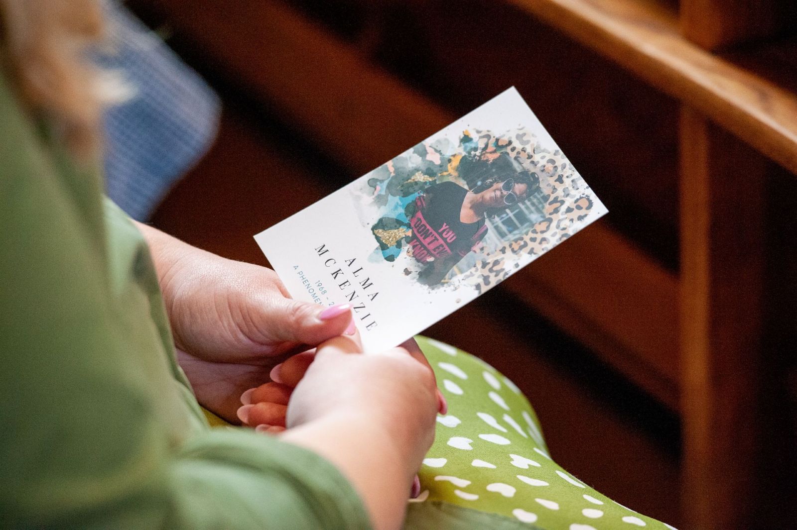 Woman at a funeral holding colourful order of service